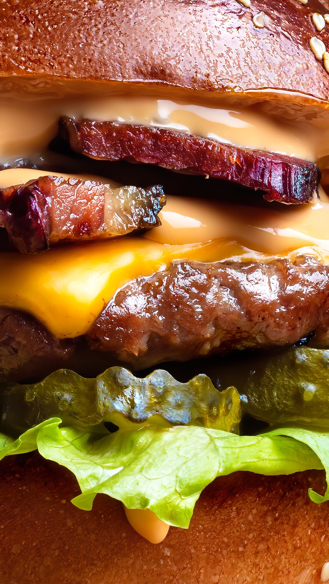 Close-up of a loaded bacon cheeseburger with melted cheese and lettuce on a brioche bun, street food burger photography Southampton