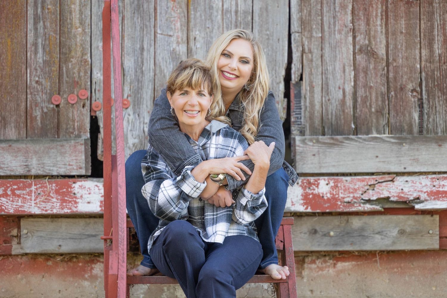Mother and daughter sitting on the steps of an old barn