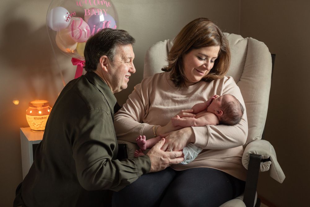 Intimate family moment in dimly lit room with pink balloons.