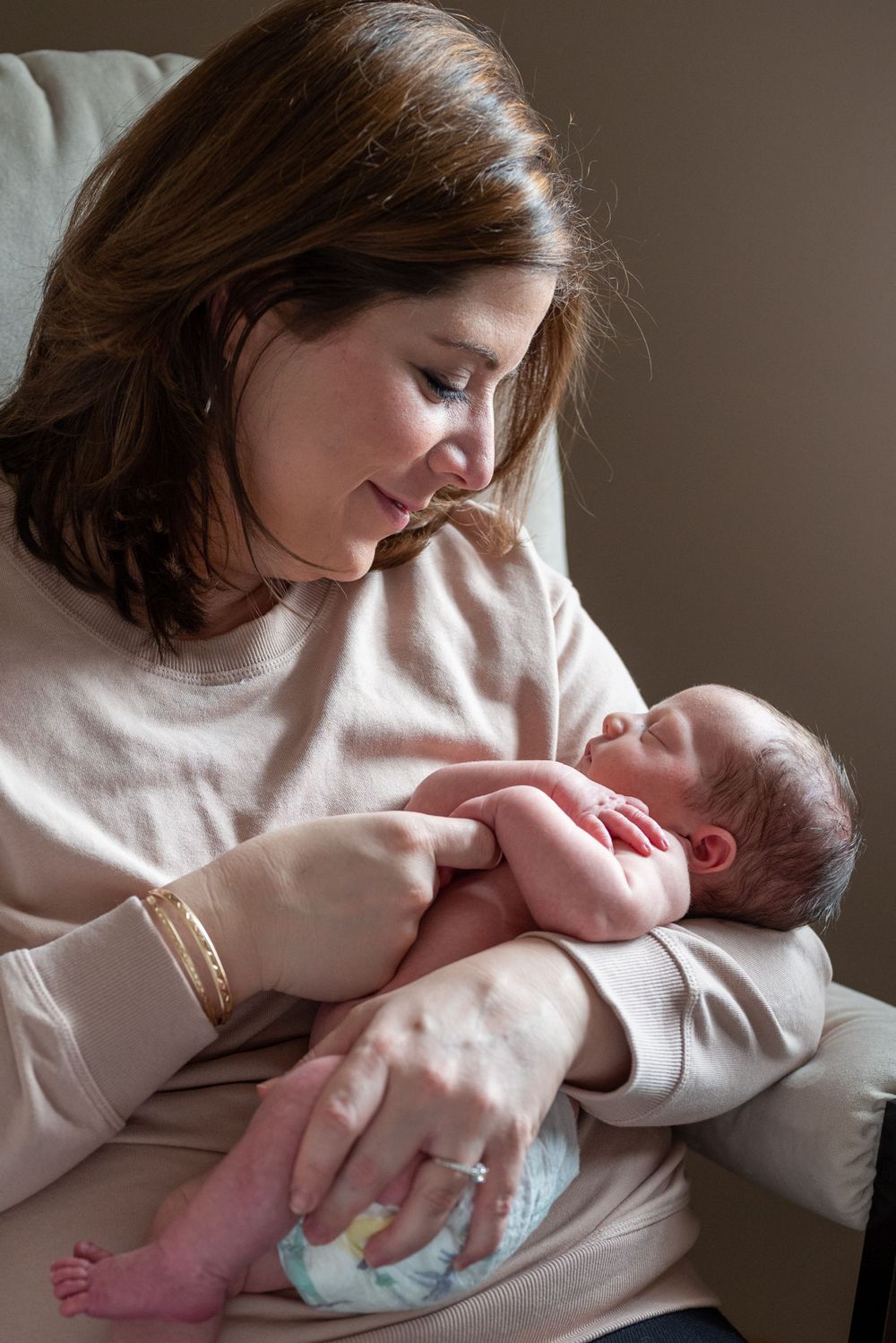 Tender moment between parent and newborn in natural window light.
