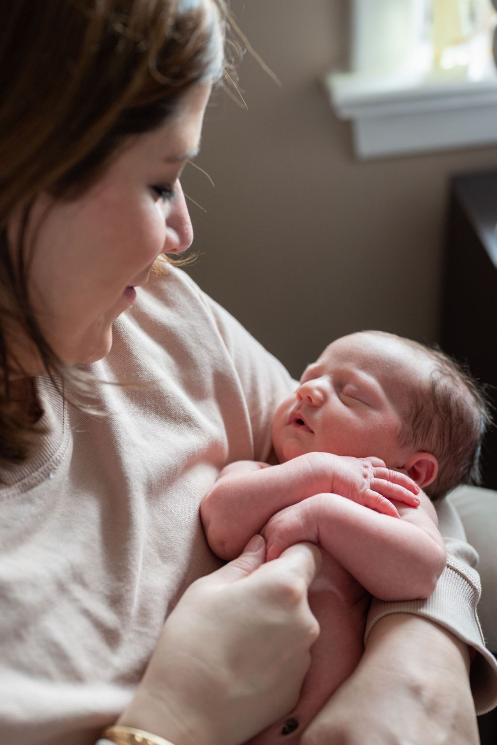 Intimate bonding moment with sleeping newborn in soft natural light.