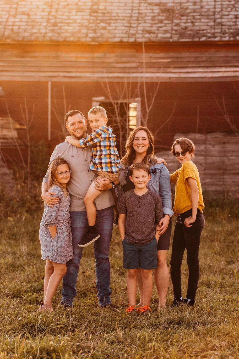 A white family smiles at the camera with golden hour light shining on in the background.