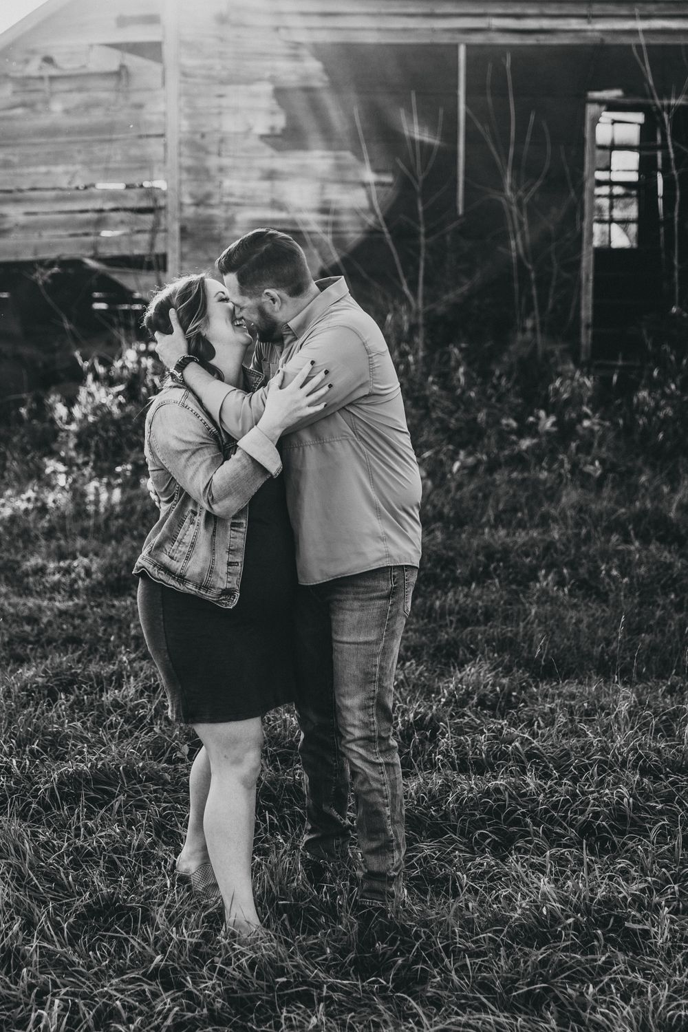 Black-and-white photo of the moment before a kiss. Dad's hand rests on the back of mom's head as she holds onto his arm.