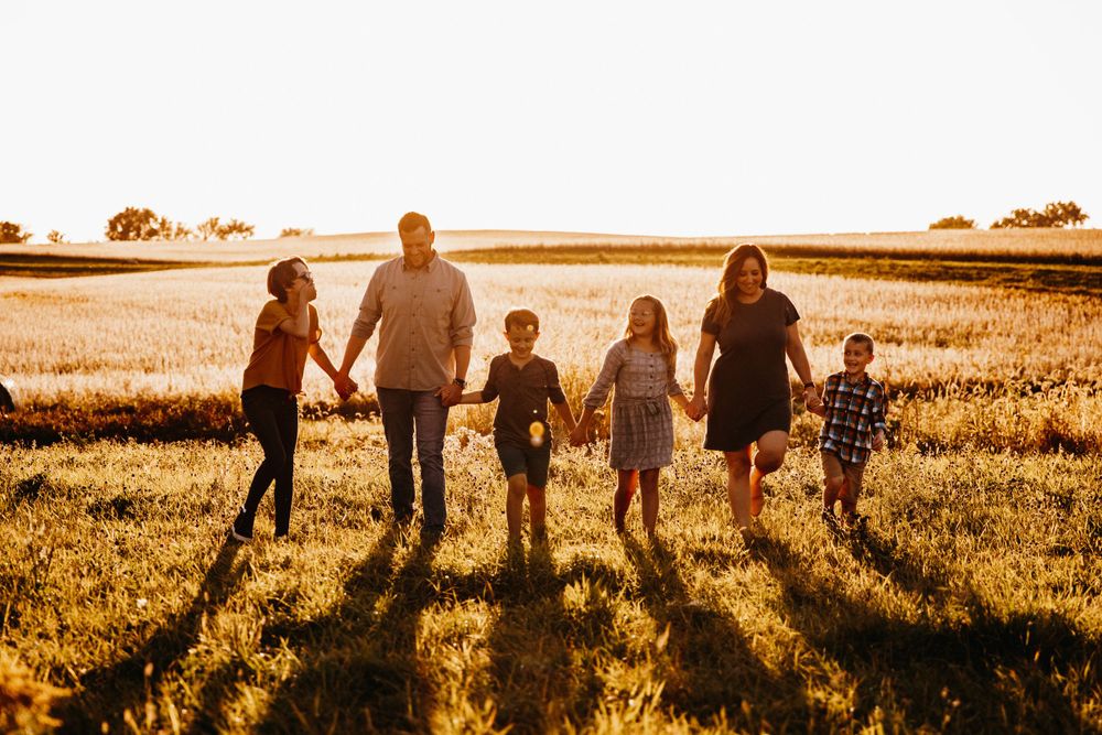 A family laughs together as they walk hand-in-hand during golden hour.