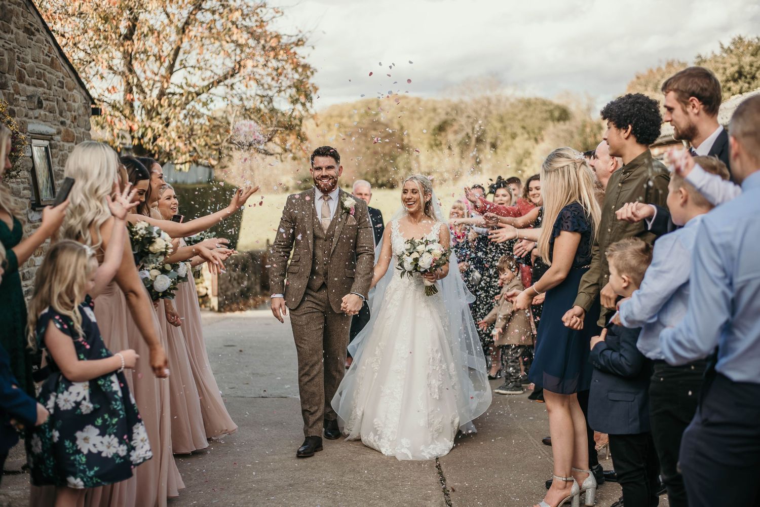 Bride and groom happily walk through confetti shot at Hyde bank wedding farm Stockport