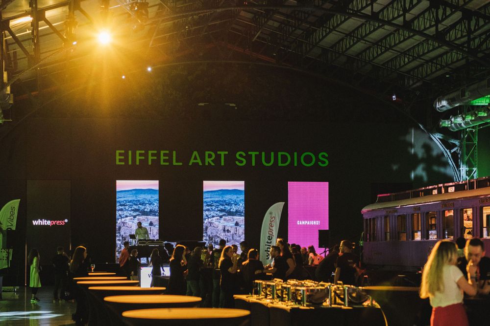 Event space at Eiffel Art Studios with crowd gathering under warm lighting.
