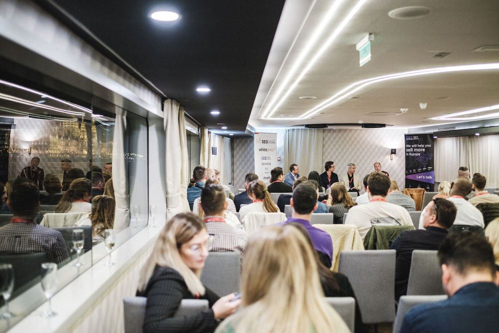 Crowded conference room with attendees seated in rows during presentation.
