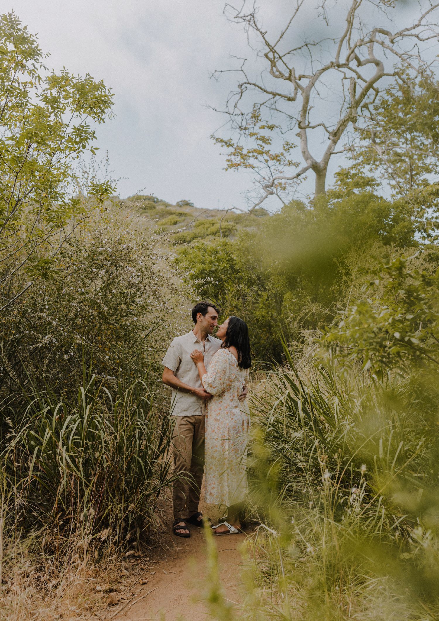couple sharing a kiss with background of blurred flowers and trees