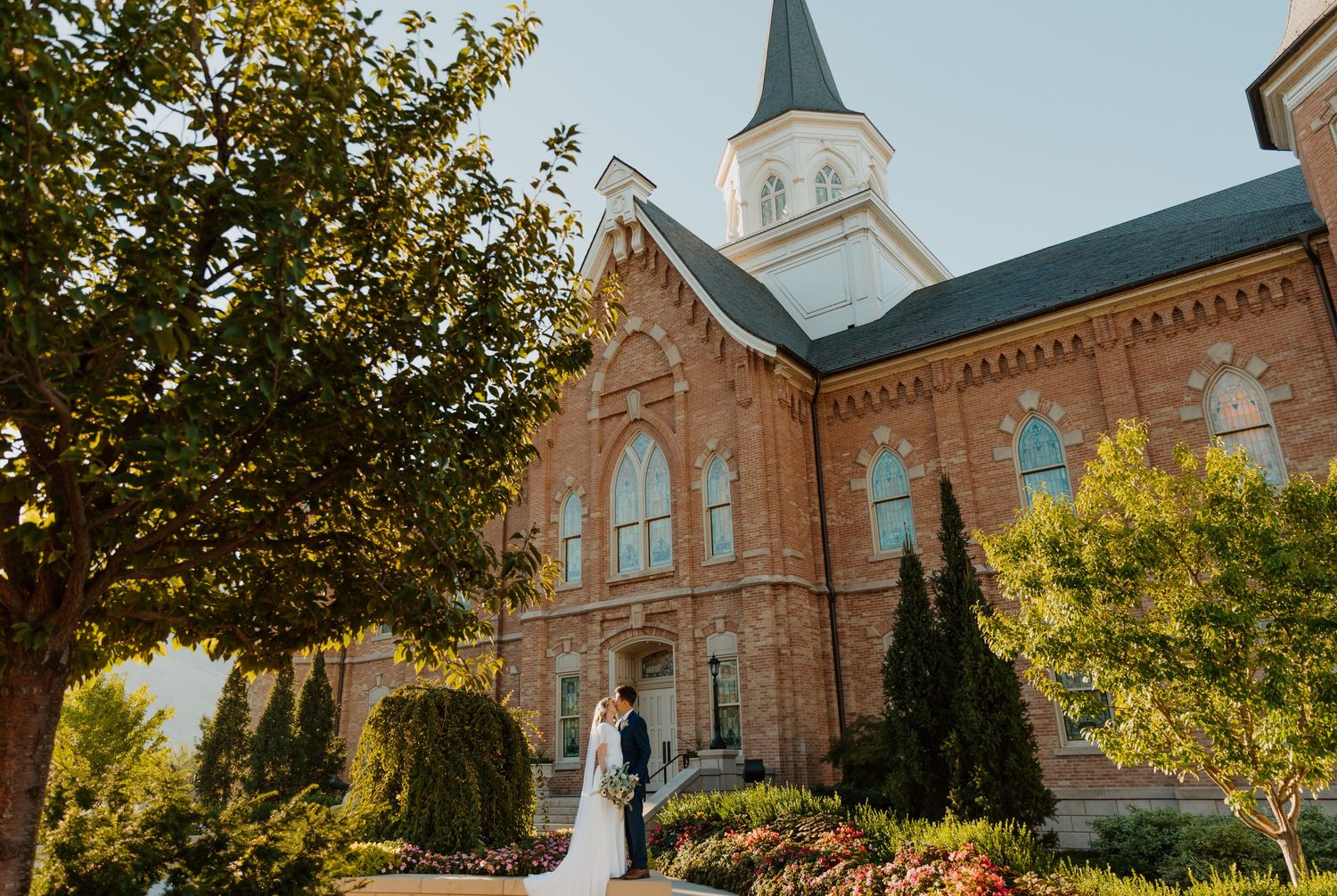Wedding ceremony in front of a historic brick church with ornate architecture and steeple.