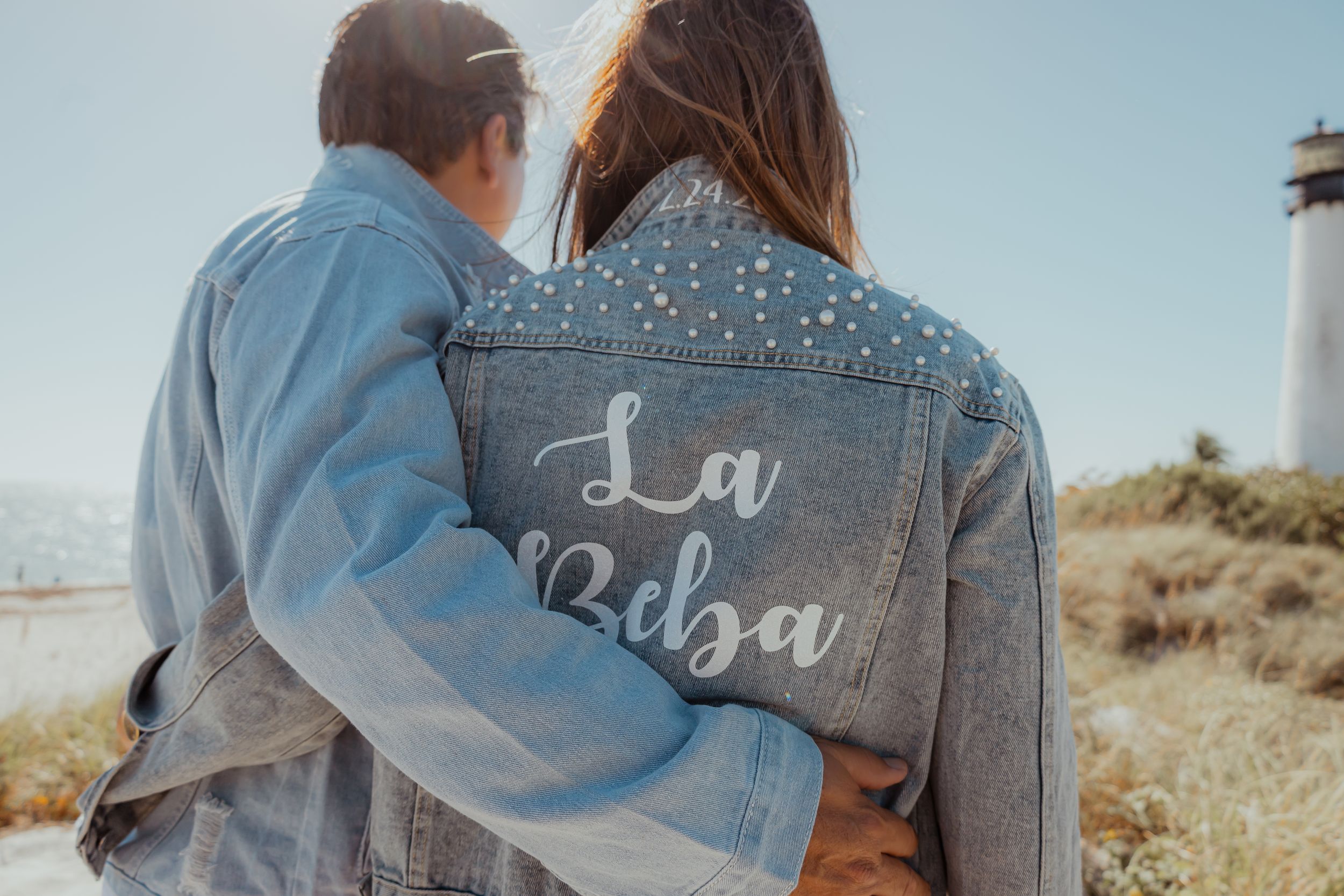 Couple wearing matching denim jackets with 'La Boba' text embroidered on back.
