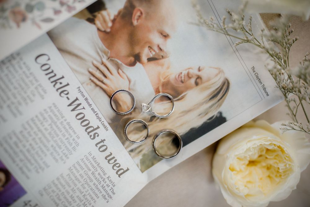 Wedding rings arranged on magazine page with roses and delicate floral decor.