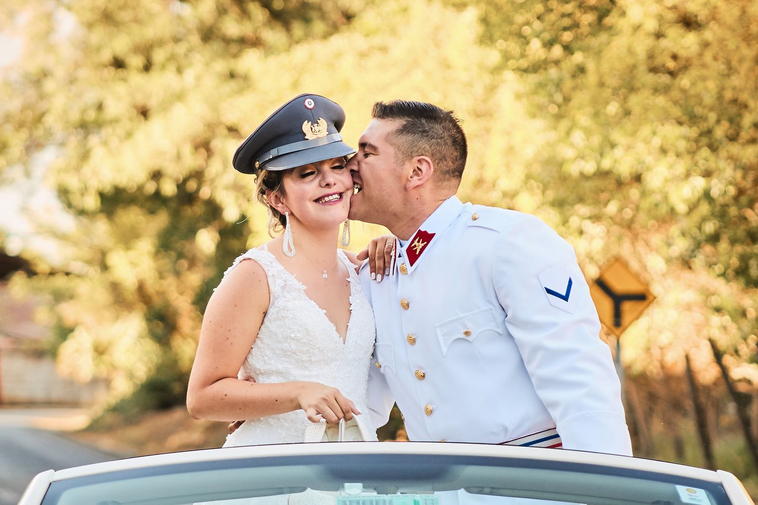 Military wedding couple sharing joyful moment in convertible car outdoors.