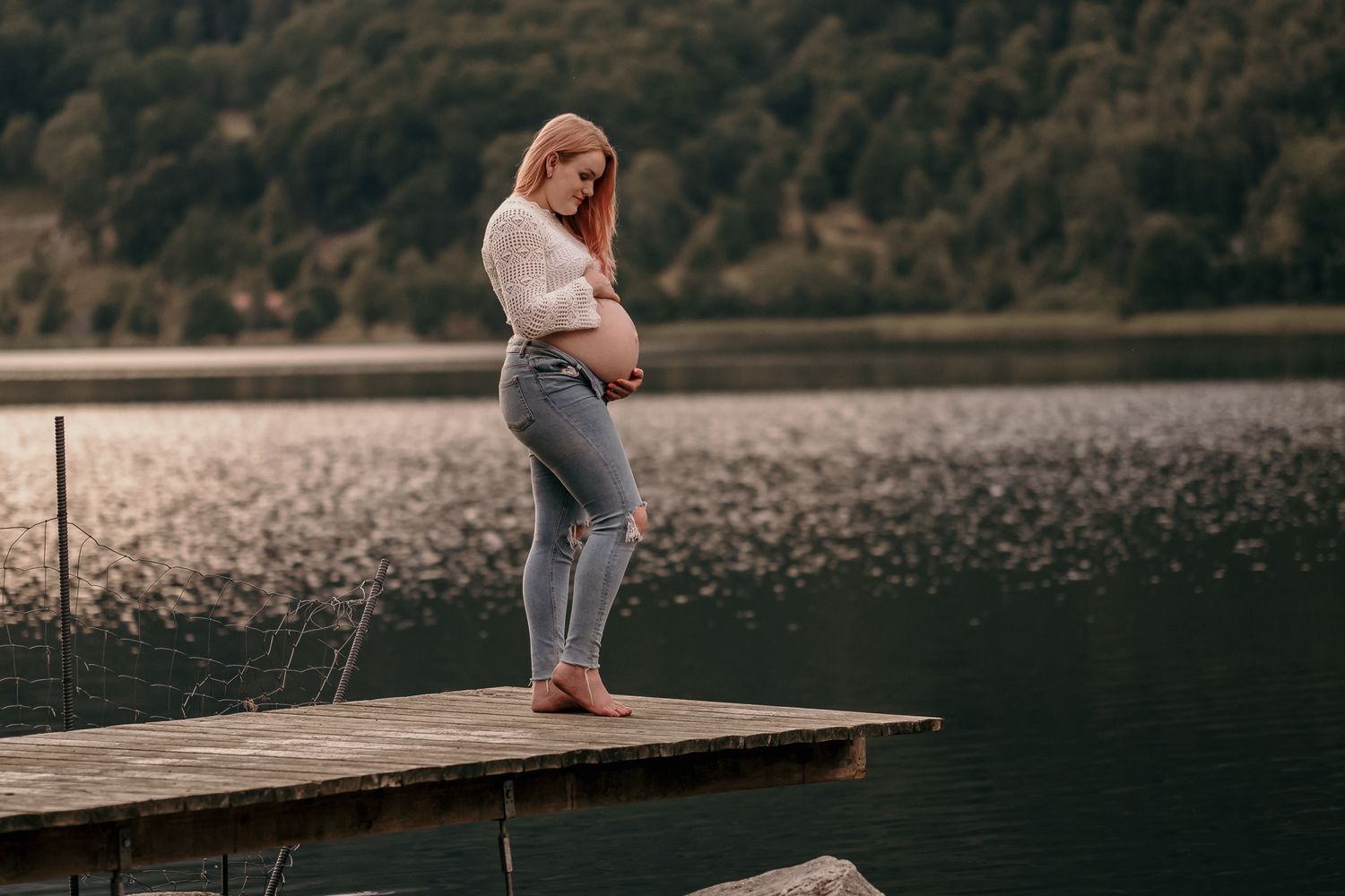 Gravid kvinne på brygge ved koselig vann
