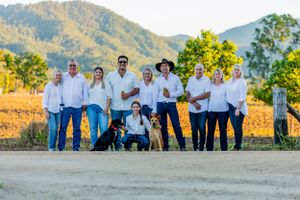 A group in coordinated blue jeans and white shirts poses together on a dirt path with mountains in the background.