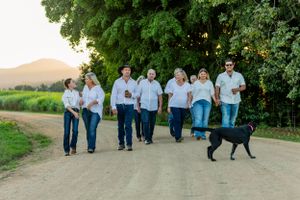 People in matching outfits walking on a dirt road with a black dog during golden hour.
