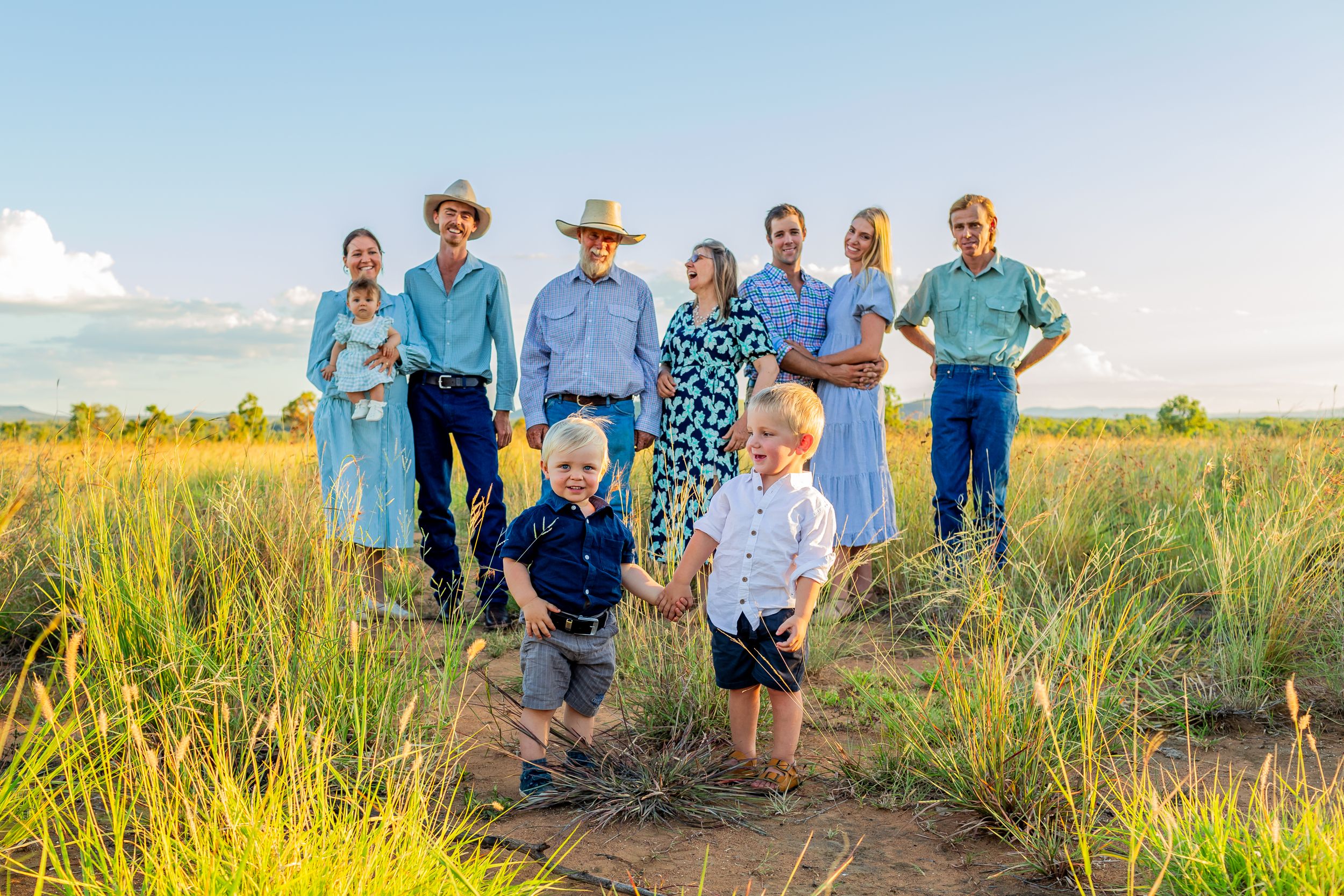 Candid family portrait with children playing in grassy field.