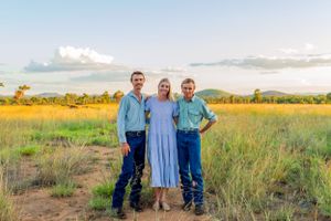 Three people in casual attire standing in golden grass field.