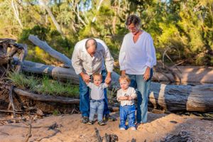Family spending time together exploring on fallen logs in a wooded area.