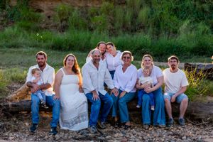 Extended family group gathered on a fallen log for outdoor portrait session.