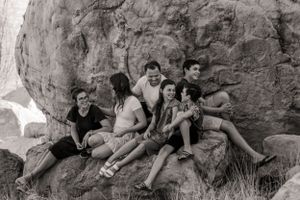 Black and white photo of people sitting casually on large rocks in an outdoor setting.