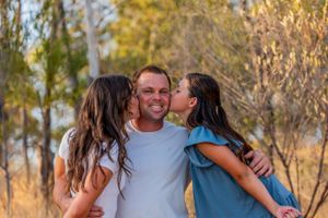 A sweet moment captured in golden light as three people share affection outdoors.