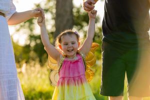 Child in a colorful dress playing outdoors during golden hour.