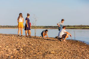 Group enjoying leisure time by a serene lake shore on a sunny day.