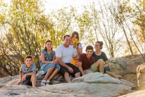Group relaxing together on rocky terrain with autumn foliage in the background.