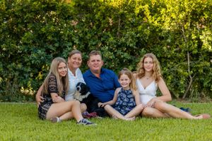 A family relaxes on grass with their black and white dog during an outdoor photo session.