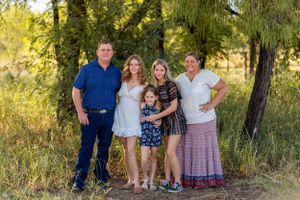 A group poses for a casual outdoor family portrait in a natural setting with trees.