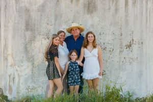 A family poses against a textured white wall during a casual outdoor photo session.