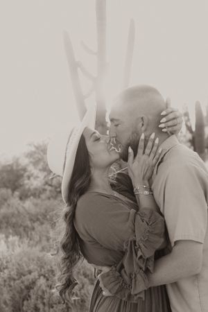 A black and white romantic portrait with desert cacti in the background.
