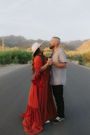 Couple sharing intimate moment on desert road with mountain landscape.