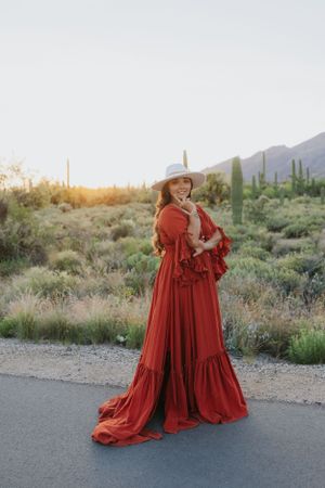 A flowing red dress creates dramatic movement against a desert backdrop with saguaro cacti.