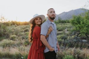Two people share a tender moment during a desert photoshoot with mountains in the background.