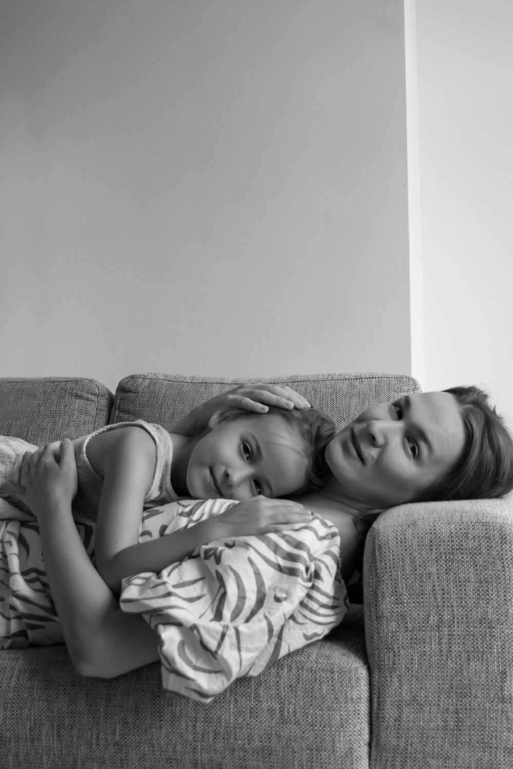 Mother an daughter laying down a sofa and hugging each other in Cambridge, UK