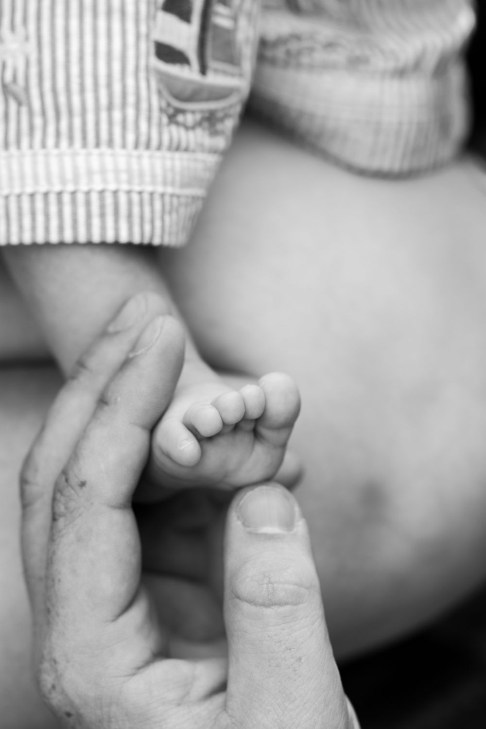 Tiny toes wrapped around father's finger, a bond that knows no bounds. Cambridge, UK