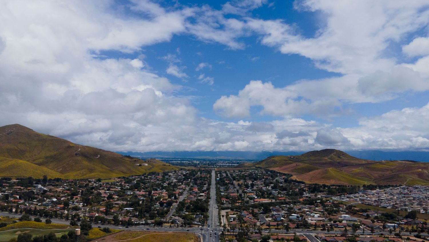 Aerial panoramic view of a small mountain city with a main road stretching into the horizon.