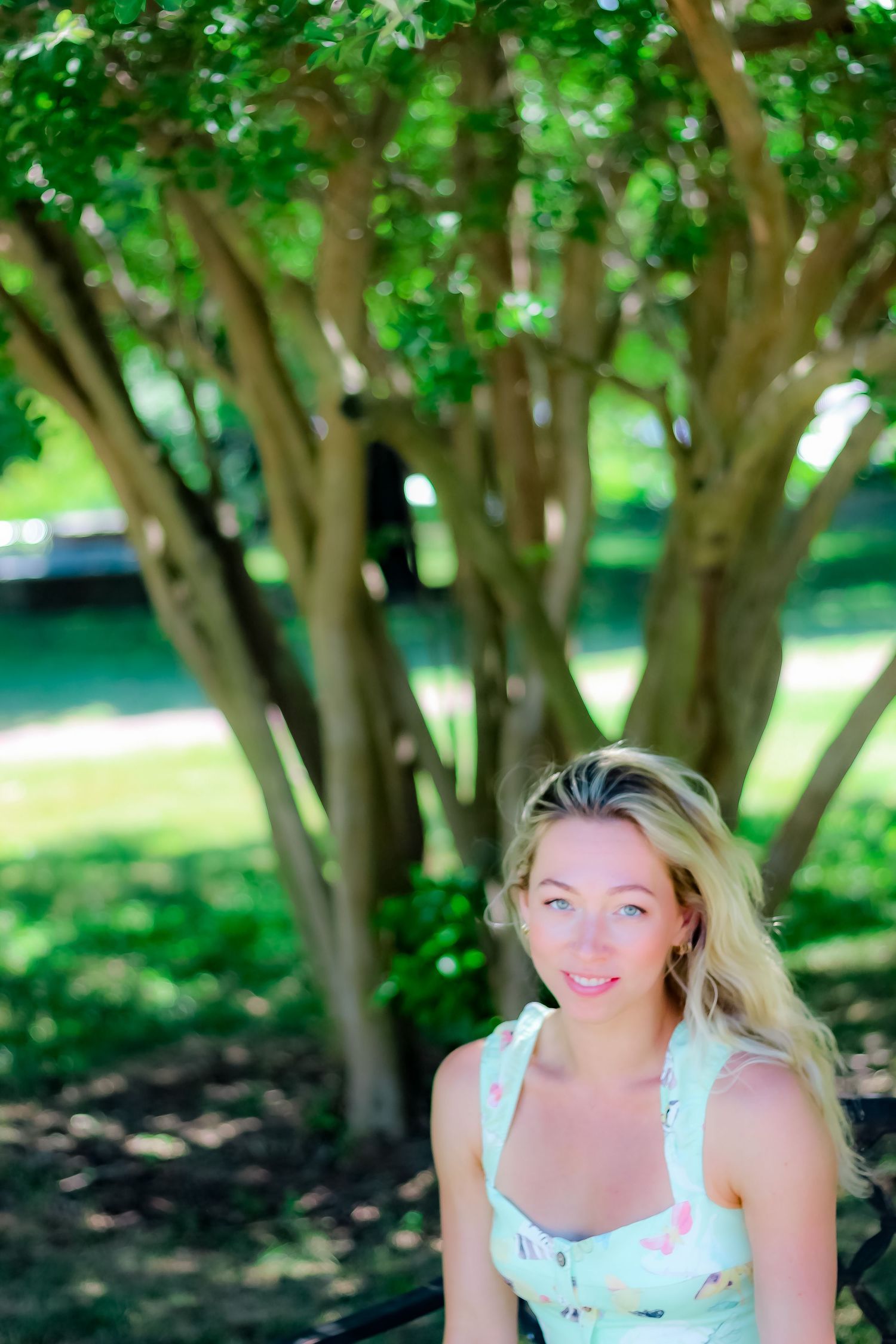 Portrait under a green leafy tree with soft natural lighting.