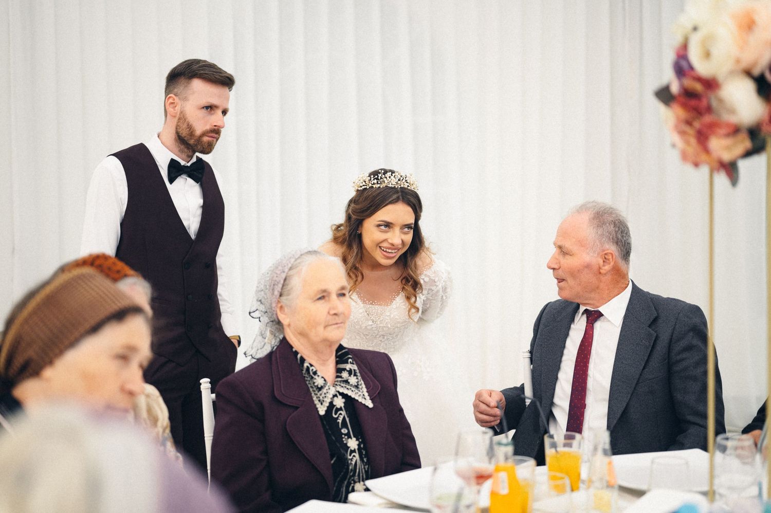 Elegant wedding reception scene with guests dining at decorated tables.