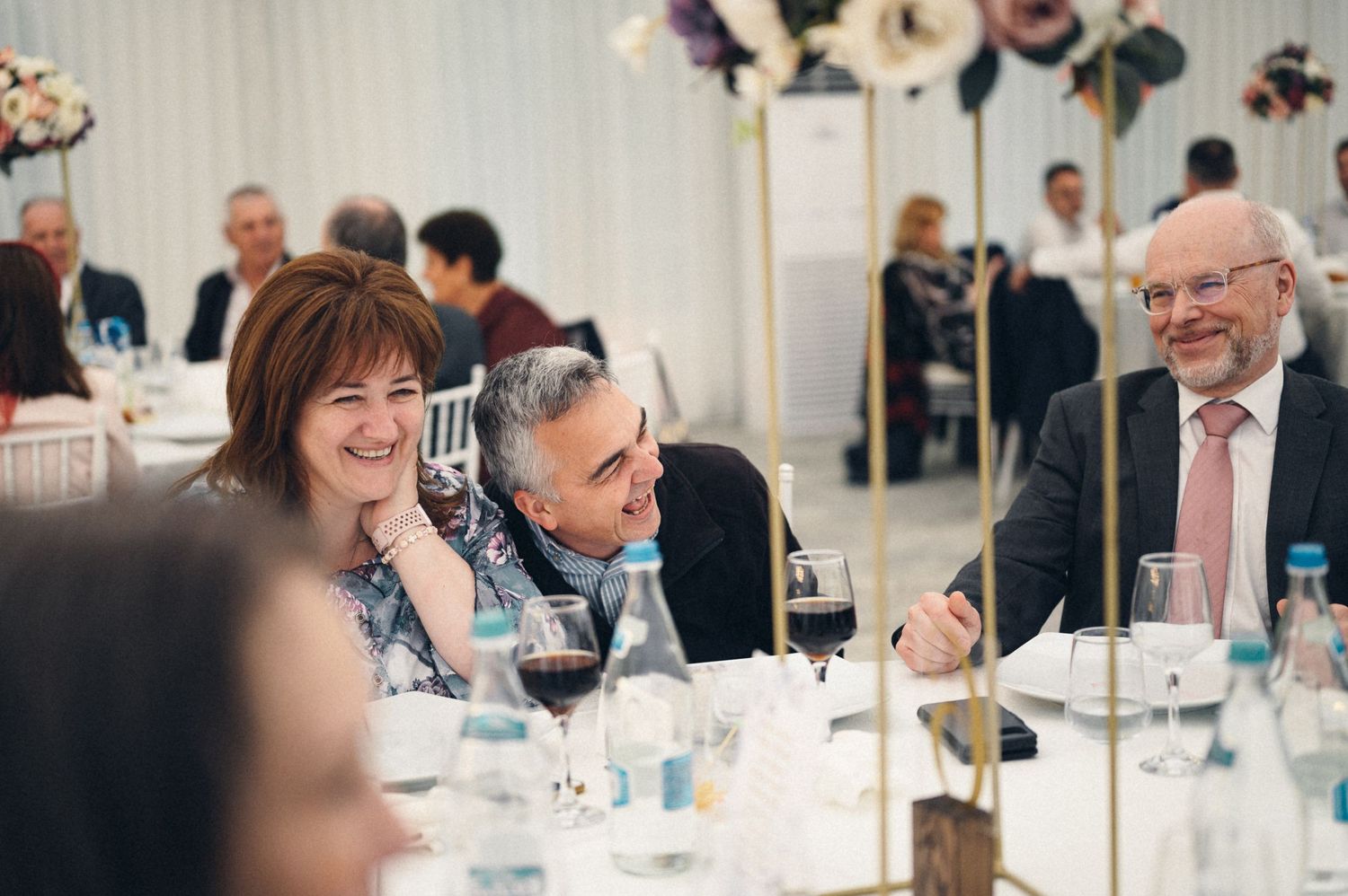 Candid moment of guests laughing during wedding reception dinner.