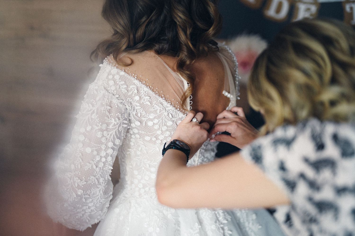 Close-up of detailed beadwork being adjusted on white wedding dress.