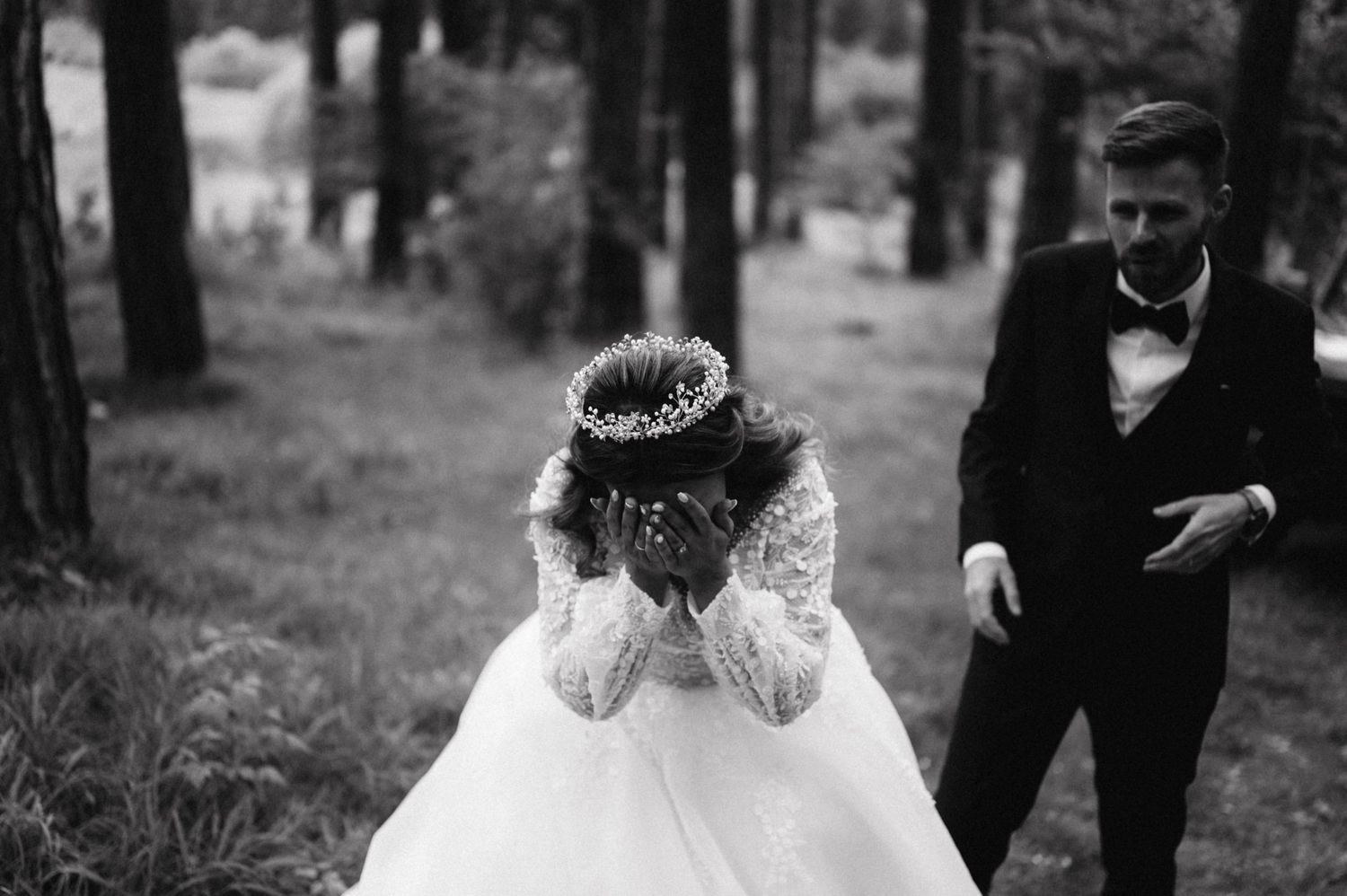 Black and white emotional wedding moment captured in forest setting.