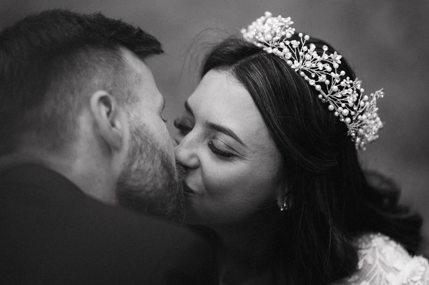 Intimate black and white portrait of wedding couple sharing kiss in natural lighting.