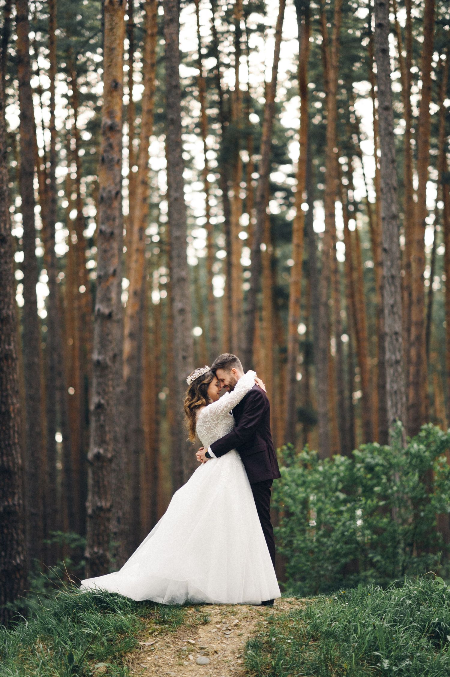A romantic wedding moment captured in a tall pine forest setting.