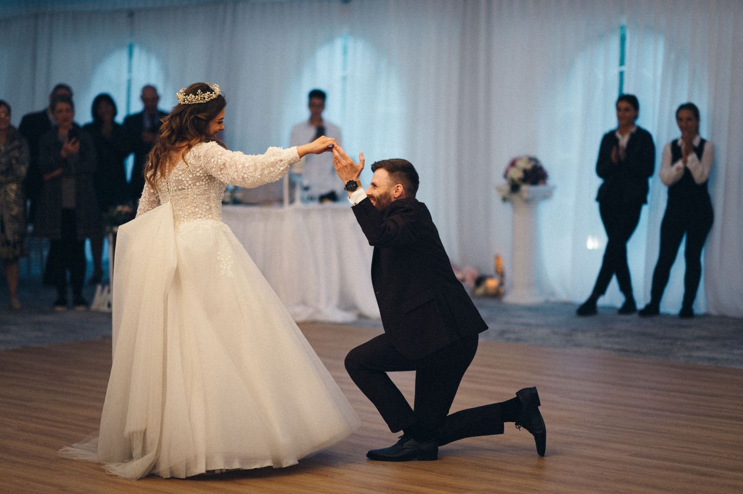 A playful wedding dance moment captured under white tent draping and string lights.