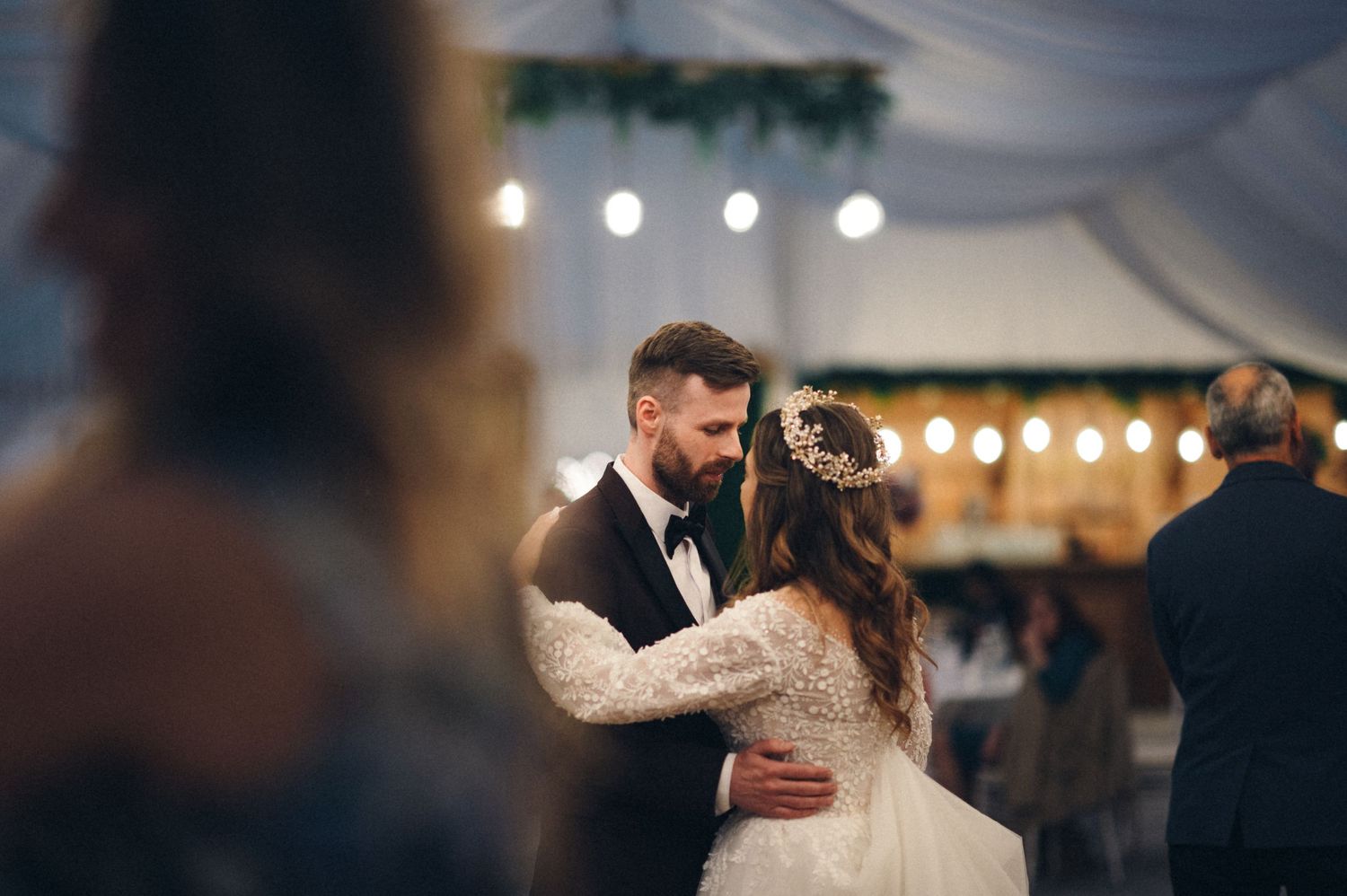 A couple shares their first dance as newlyweds under romantic string lights.