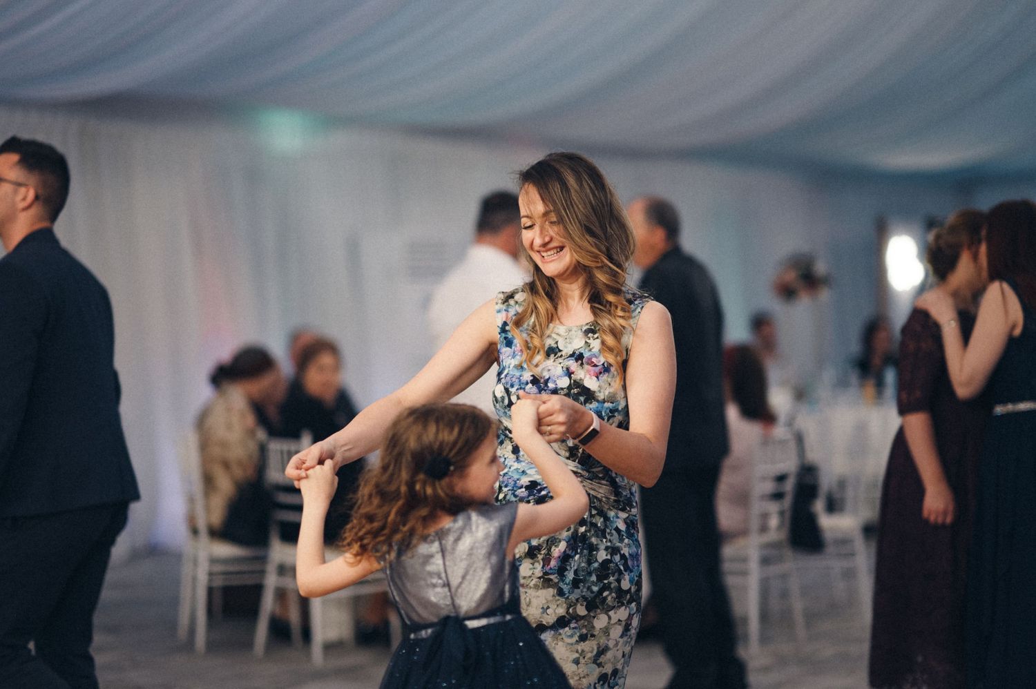 Wedding guests enjoying dancing together at an indoor reception venue.