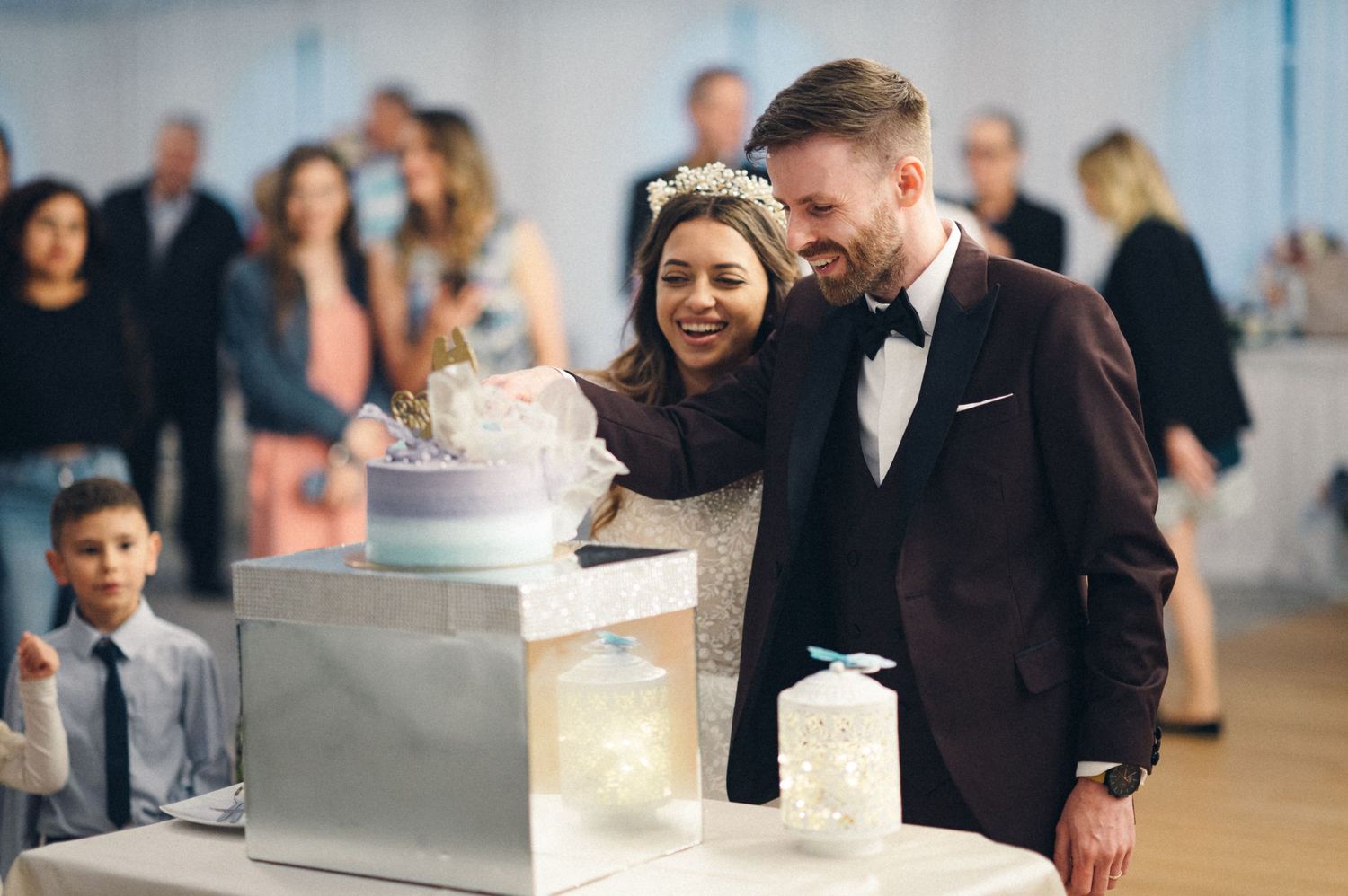 Newlyweds share a joyful moment while cutting their elegant tiered wedding cake.