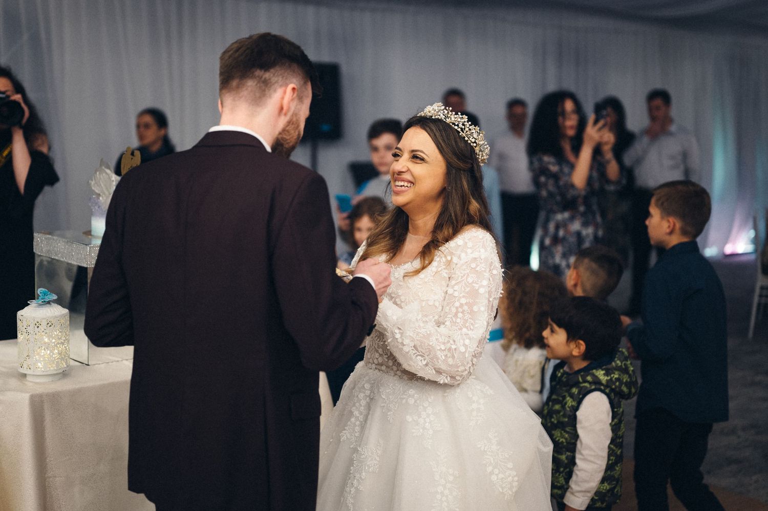 Bride in lace dress dances with groom during wedding reception.
